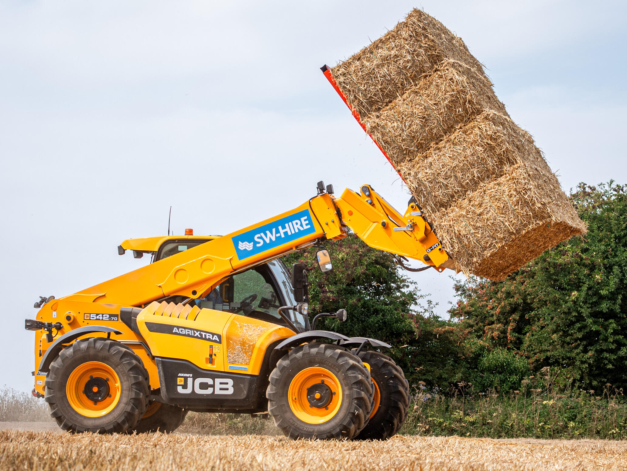 JCB 542-70 AgriXtra with 4 straw bales stacked on the grab