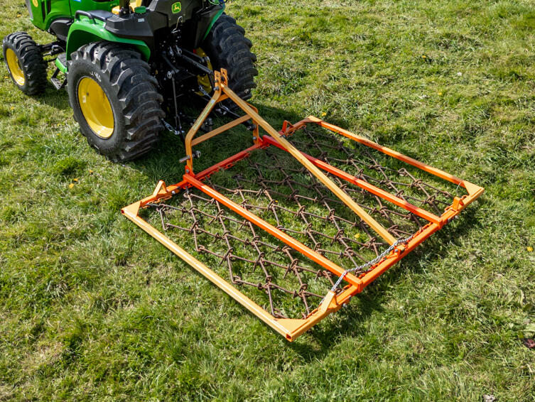 chain harrow attachment on john deere 3038E compact tractor in field