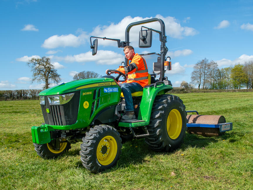 John Deere 3038E Compact Tractor with roller attachment in field