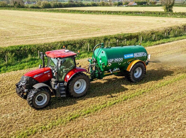 Major 2600 slurry tanker spreading slurry with the splash plate in a grass field, towed by a Case tractor