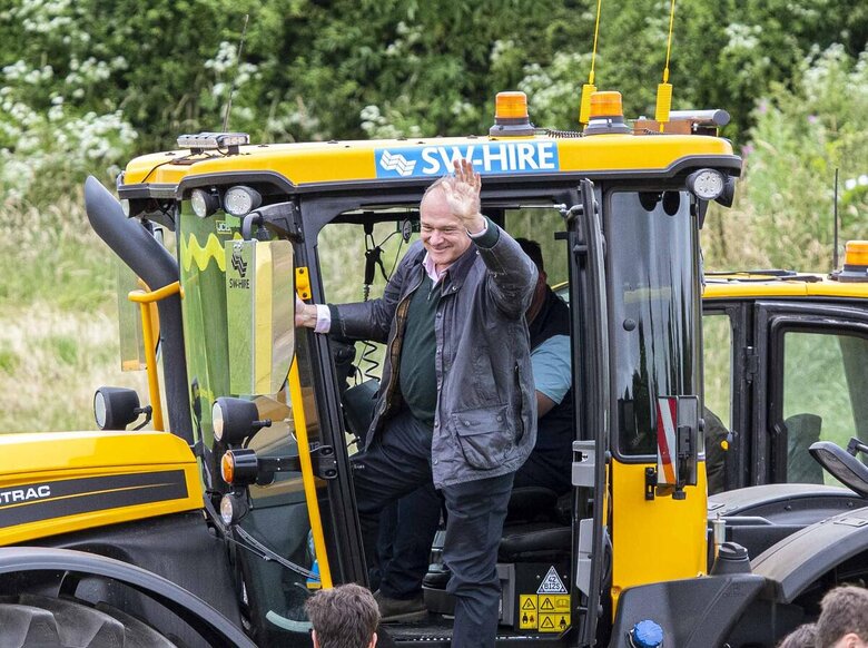 Sir Ed Davey waving from a SW Hire JCB 4220 iCON Fastrac
