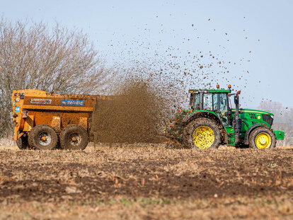 Richard Western SDS24 side discharge muckspreader spreading muck in stubble field