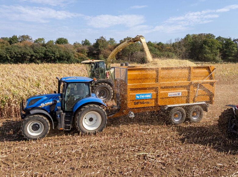 SW-Hire SF14HS silage trailer pulled by a New Holland tractor driving next to a Krone forager harvesting maize