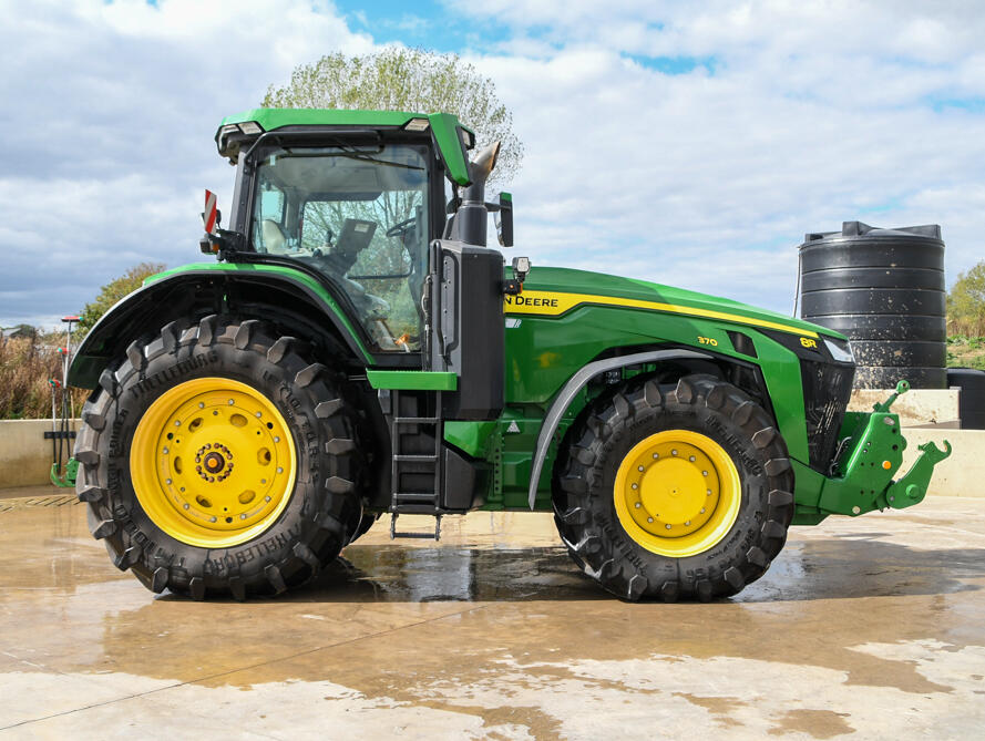 John Deere 8R370 tractor parked on a concrete pad