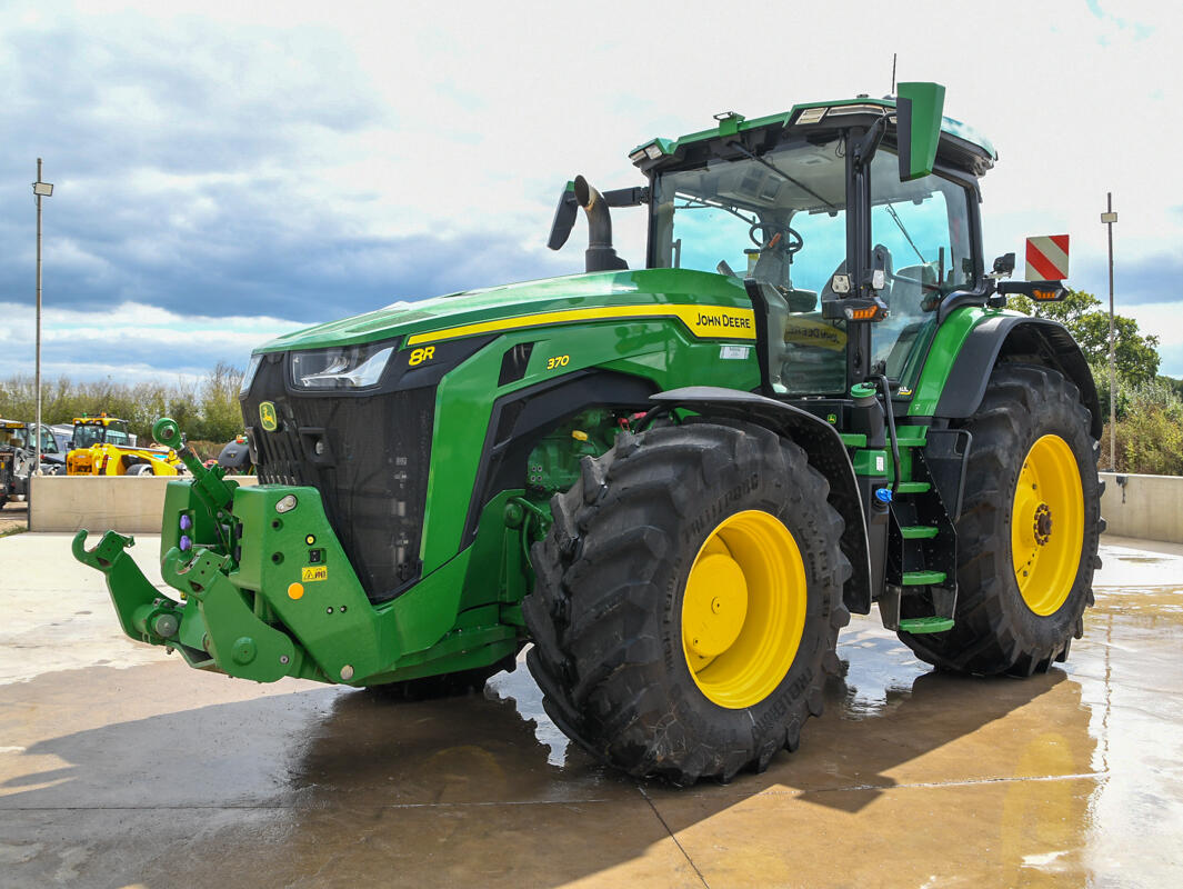 John Deere 8R370 tractor parked on a concrete pad