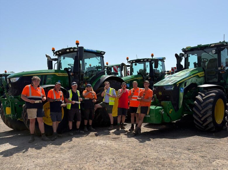 SW Hire workshop team eating a Marshfield Moment ice cream in front of john deere tractors